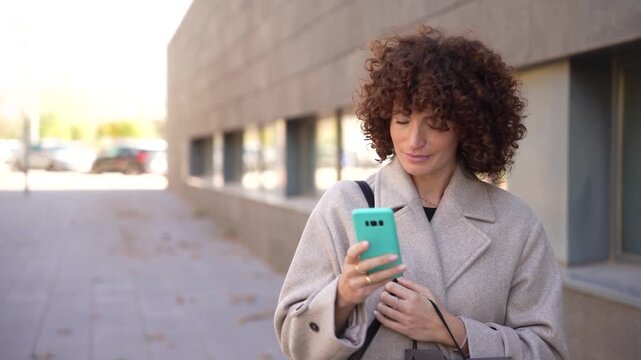 A confident woman sporting beautiful curly hair enjoys walking outdoors in the city