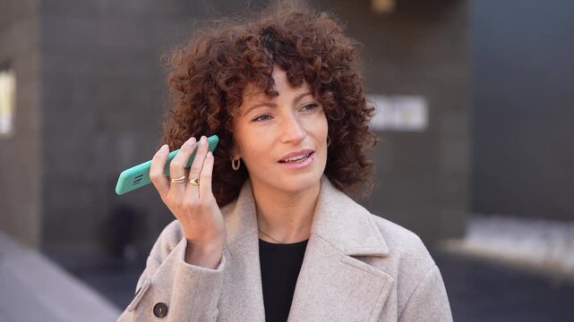 A young woman using her smartphone outdoors in a modern urban setting, showing a lifestyle