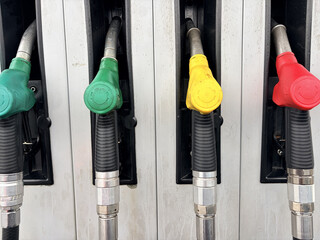 Close-up of colorful fuel pump nozzles holstered at a gas station © Vovmar