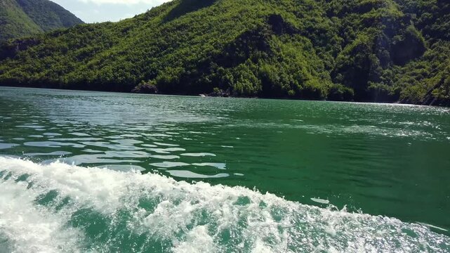 Stunning view of the Albanian Alps from a boat navigating the turquoise waters of Lake Koman, a famous landmark in northern Albania