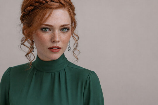 Freckled redhead woman with green eyes in emerald outfit, beauty portrait with copy space
