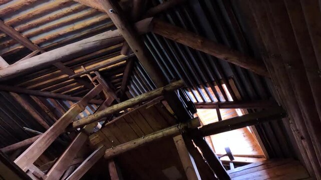 Wooden mill interior with beams and sunlight.