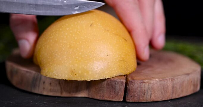 A golden pear on a cut tree, this ripe pear object is represented as thin slices on a brown background of dry wood.