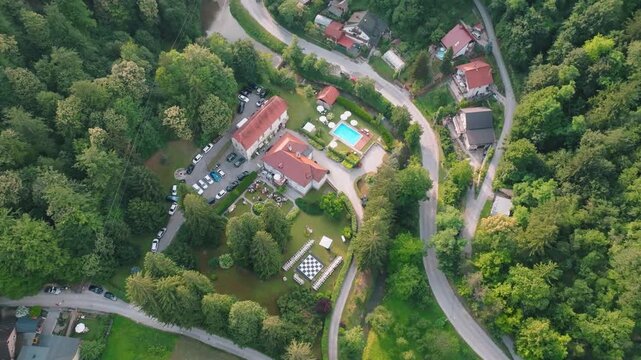 Aerial view of Kurija Hamor surrounded by lush forest, a swimming pool, and parking area in Samobor, Zagrebacka zupanija, Croatia.
