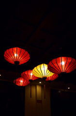 Vibrant red and yellow lanterns softly illuminate a dark room with a warm, cozy glow © hippomyta