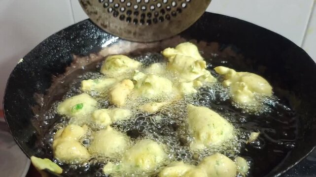 Deep Frying Indian Pakora Fritters in Hot Oil in Wok Kadhai Close Up