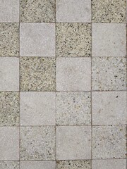 Fototapeta premium A top-down view of a checkered terrazzo floor showcasing alternating light beige and speckled stone tile patterns.