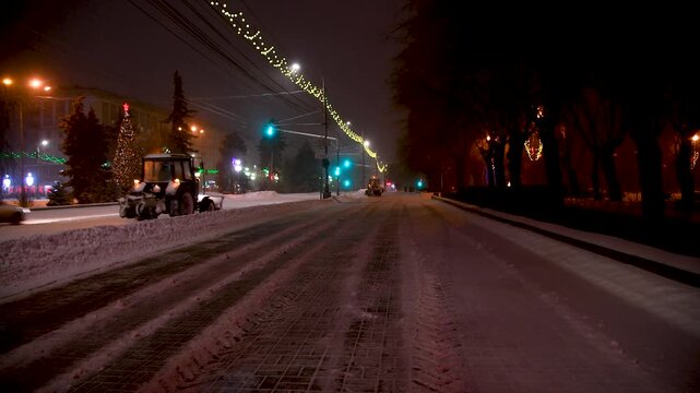 Large snow tractor at work on the evening streets of the city