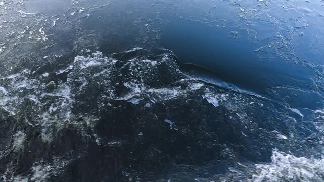 Waves from a boat sailing on a cold winter river
