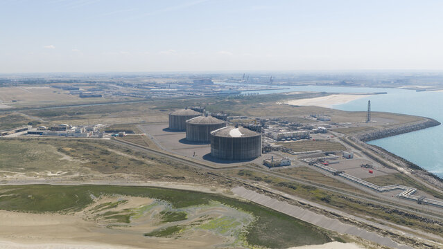 Aerial view of the Dunkirk LNG Terminal featuring large storage tanks, industrial infrastructure, and coastal facilities situated along the coastline in Loon-Plage, Hauts-de-France, France.