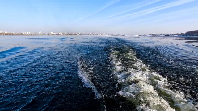 Waves from a boat sailing on a cold winter river