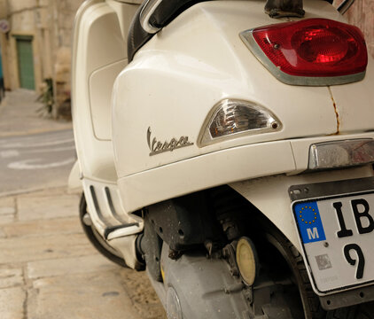 Vintage white Vespa scooter parked against the background of a shabby wall in a narrow European street in Valletta, Malta - March, 2026.