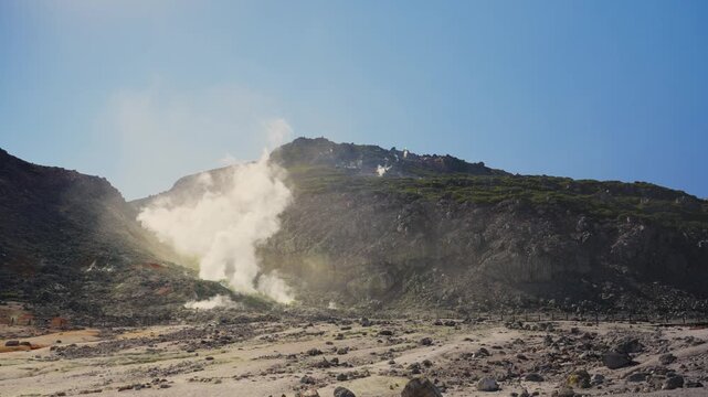 Hot steam and volcanic gases rising from fumaroles on side of a sulfur mountain, stunning display of geothermal energy in Akan Mashu National Park, Hokkaido, Japan, on a sunny day