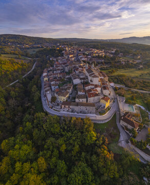 Aerial view of the historic hilltop town of San Giuliano del Sannio with stone buildings and terracotta rooftops surrounded by lush autumn forests in San Giuliano del Sannio, Molise, Italy.