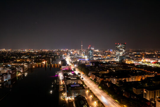 Aerial view of the illuminated Berlin skyline at night featuring the Spree river, the historic Oberbaum Bridge, and modern city lights in Berlin, Berlin, Germany.