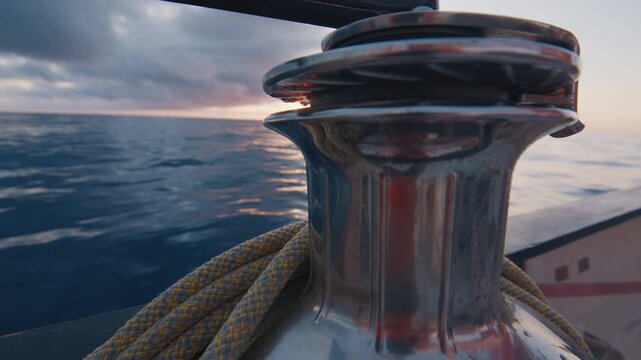 Winch with rope of the sailing boat moving in the ocean. Sunset as seen from the moving sailing boat with winch on the foreground