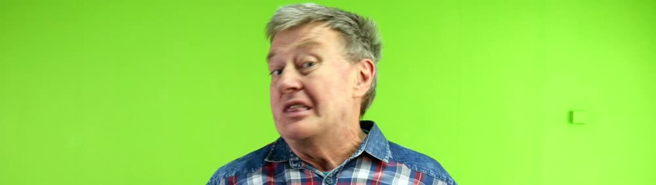 Mature man expresses anger frustration and stress yelling loudly no with an open mouth on a green virtual set background.