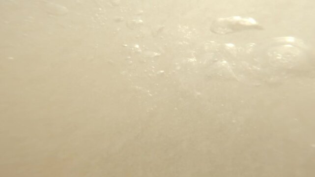 Close waterline footage shows an adult man as a rising tropical swell submerges the action camera, filling the lens with bubbles before he reappears in sunlit surf near Mirissa, Sri Lanka.