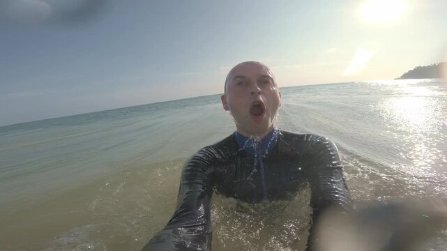 At water level, a swimmer faces the camera as a green tropical wave breaks over him near Mirissa Beach, Sri Lanka, briefly submerging the lens in bubbles before he resurfaces.