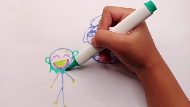 Close-up footage of a human hand drawing a cute cartoon character using a green marker on white paper. Creative illustration process suitable for education, art, children's content, creativity, doodli