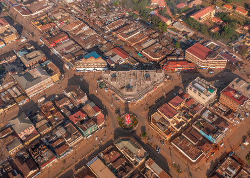 Aerial view of the clock tower roundabout in Mbale, featuring surrounding commercial buildings, dense urban rooftops, and street networks in Mbale, Eastern Region, Uganda.