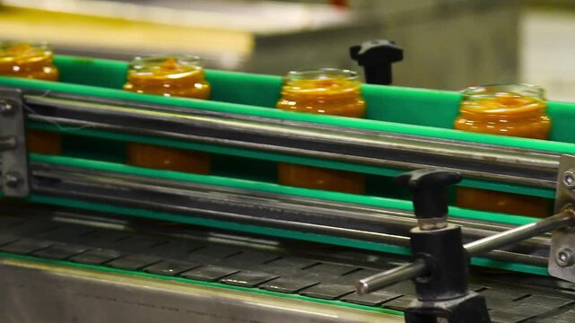 A conveyor belt with cans of mashed vegetables moving along it.