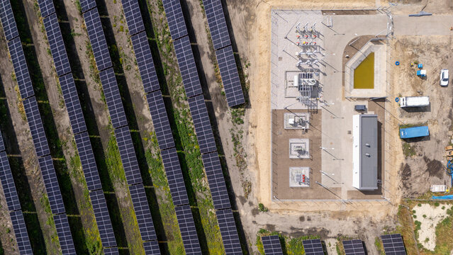 Aerial view of a large solar farm with rows of photovoltaic panels and an electrical substation in Grudziadz, Kuyavian-Pomeranian Voivodeship, Poland.