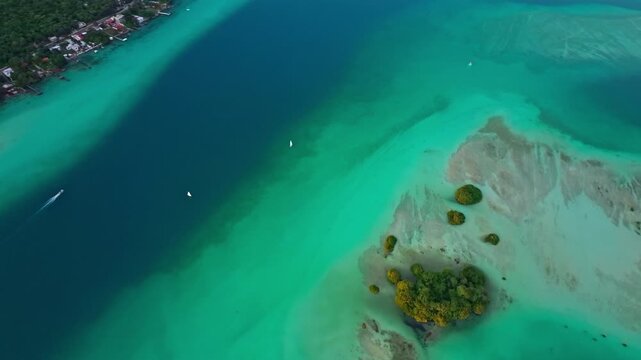 Top-down aerial view of a white sandbar and mangrove island in the turquoise Bacalar lagoon, Mexico, pale shoals swirling through the clear water.