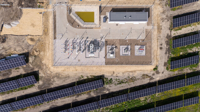Aerial view of a solar power plant with rows of photovoltaic panels and a central electrical substation in Grudziadz, Kuyavian-Pomeranian Voivodeship, Poland.