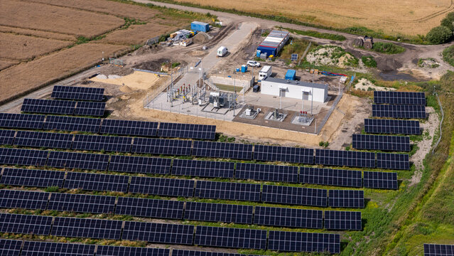 Aerial view of a solar farm with rows of photovoltaic panels and an electrical substation in a rural landscape in Grudziadz, Kuyavian-Pomeranian, Poland.