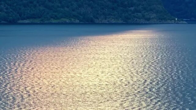 Yacht crossing sunlit fjord with shimmering water in Aurland Norway