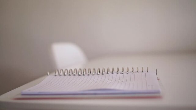 hand picking up pen from spiral notebook on desk. Business, writing, and office concept footage, ready to take notes or sign document.