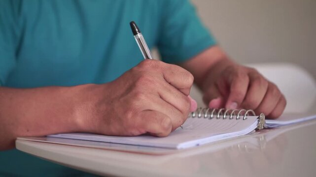 A hand writes in a notebook, realizes an error, crosses it out, and tears the page away. Great for education, writing, creativity, and self-improvement concepts.