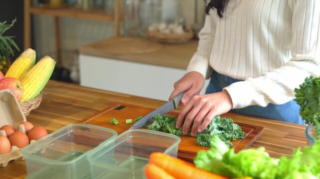 Woman Chopping Fresh Kale on Wooden Cutting Board for Healthy Meal Prep in Modern Kitchen