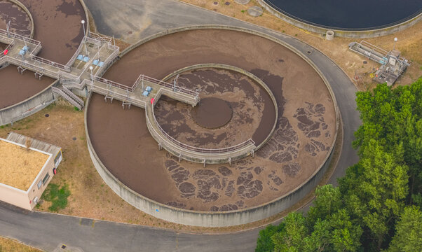 Aerial view of a circular secondary clarifier tank for biological wastewater treatment and sludge separation at an industrial facility in Portes-les-Valence, Auvergne-Rhone-Alpes, France.