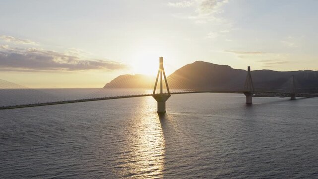 Charilaos Trikoupis Rio Antirrio Bridge over Rion Strait at sunset behind mountain backdrop, Rio, Antirrio, drone shot