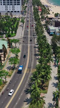 Aerial view of the road and city along My Khe Beach in Da Nang, Vietnam, showing the coastal road, buildings, sandy beach and ocean - drone, vertical shot