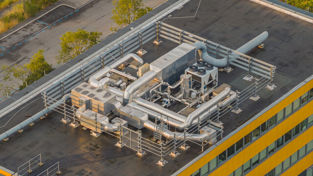 Aerial view of rooftop HVAC equipment featuring industrial ventilation ducts, cooling units and mechanical systems on a modern commercial office building in Valence, Auvergne-Rhone-Alpes, France.