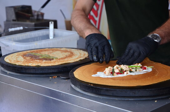 a man prepaers thin pancaces with filling