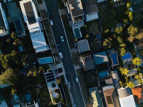 Aerial view of residential houses with swimming pools and solar panels along a suburban street in Northern Beaches Council, New South Wales, Australia.