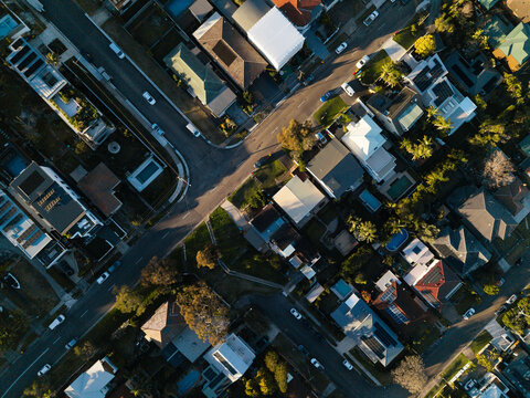 Aerial view of residential houses with swimming pools, lush trees, and streets in Northern Beaches Council, New South Wales, Australia.