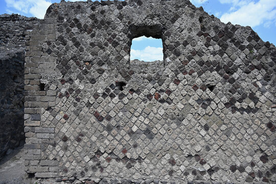 Ancient Wall in Pompeii Archaeological Site with Diamond-Shaped Stone Bricks and Single Window