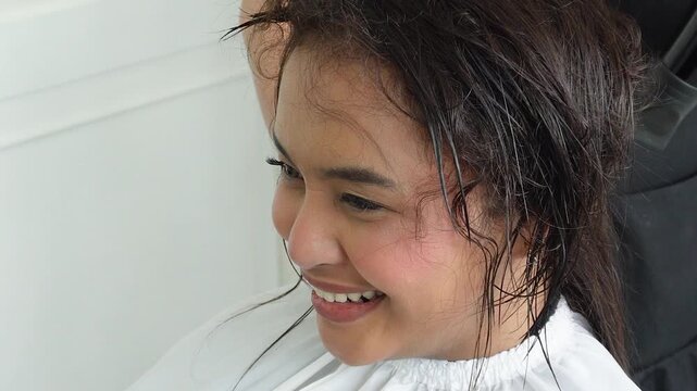 Hair stylist blow drying hair after professional rebonding treatment for Southeast Asian woman in her early 20s