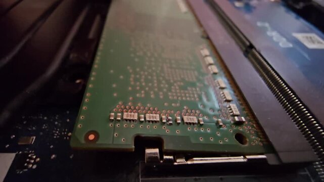 Close-up of RAM memory stick being installed or removed inside a modern laptop computer hardware motherboard slot, electronic component repair and upgrade concept
