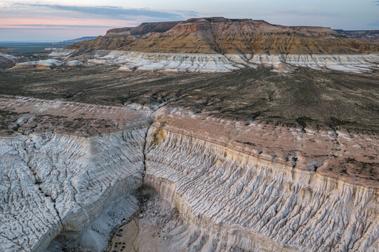 Aerial view of the dramatic white limestone cliffs and eroded canyons of the Tuzbair salt flats in the vast desert landscape of Mangystau District, Mangystau Region, Kazakhstan.
