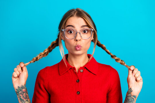 Playful young woman with braids in red polo on blue background making a kissy face for lifestyle fashion advertising