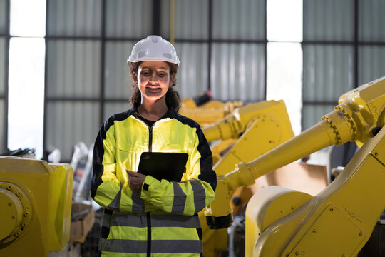 Programming, validation, and monitoring of robotic systems.Portrait of woman engineer using digital tablet connect to robotics arm system for testing and development solutions