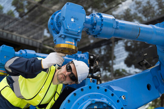 Robotics industry, programming, validation, and monitoring of robotic systems. Male engineer using digital tablet connect to robotics arm system for testing and development solutions