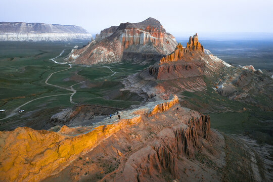 Aerial view of the dramatic rock formations of Airakty mountains in the desert landscape with winding dirt paths under golden hour light in Shetpe, Mangystau Region, Kazakhstan.