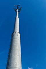 Obraz premium A solitary telecommunications tower stands against a vast expanse of bright blue sky, its antennas silhouetted against the clear atmosphere.